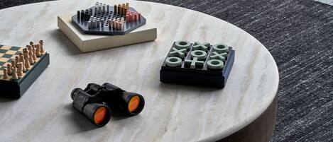 Una mesa redonda de mármol con juegos de ajedrez y unos binoculares.