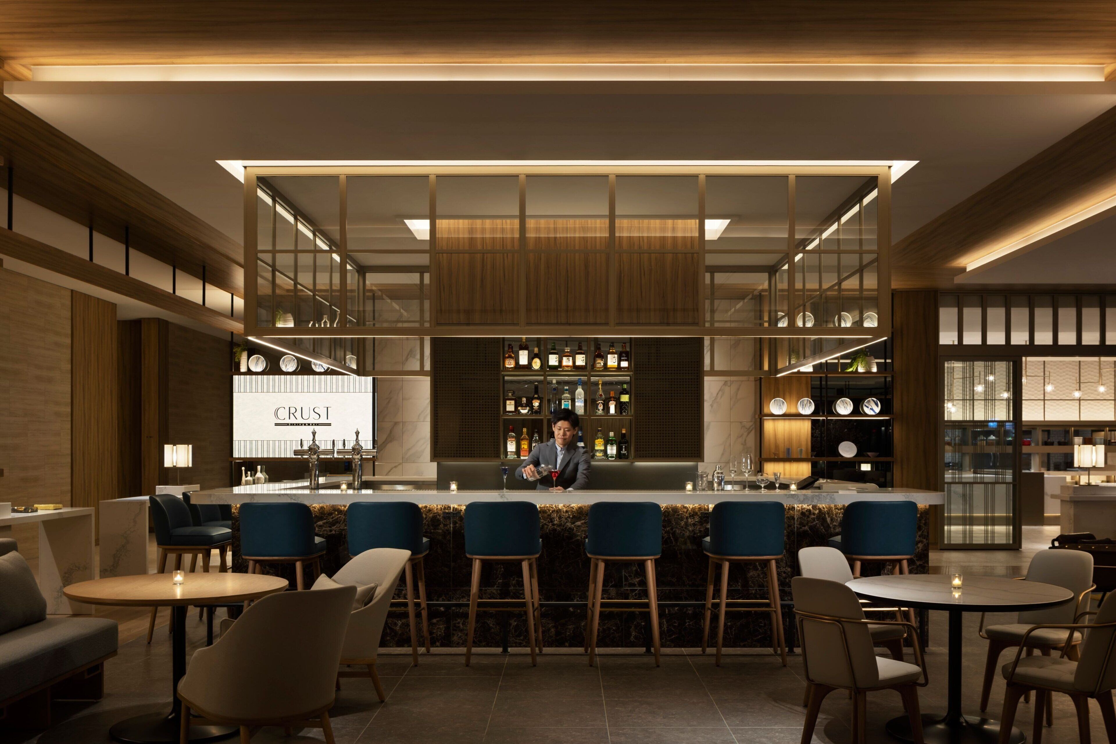 Eine moderne Bar mit Bartender, Barhocker und freundlicher Beleuchtung.