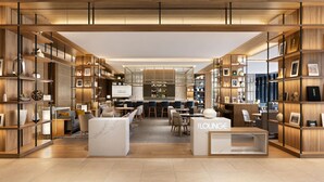A modern lounge area with wooden shelving, seating, and a bar.