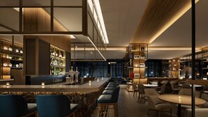 A modern bar area with a long counter, bar stools, and a seating area with tables and chairs.