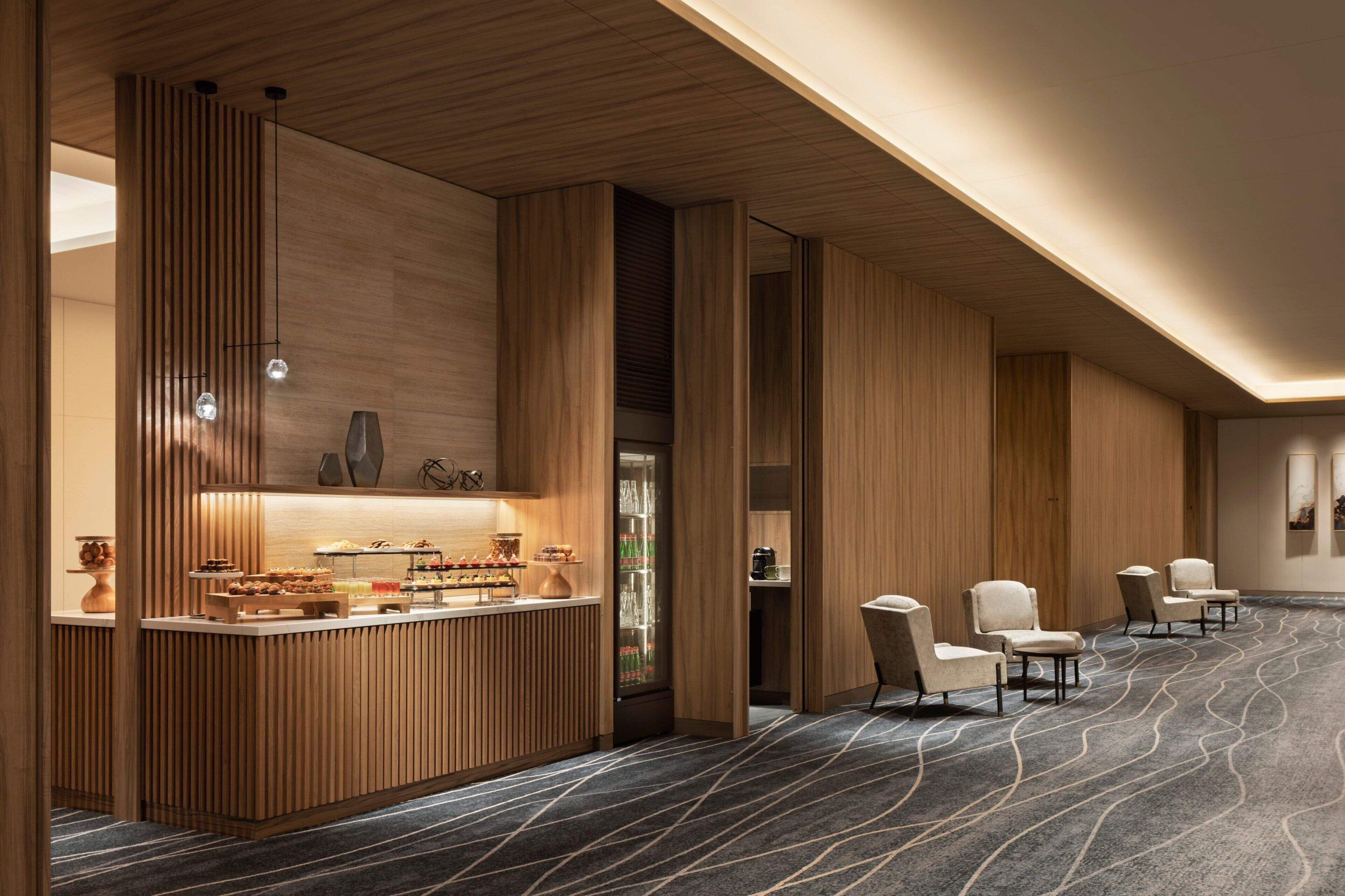 A modern hotel lobby with a reception desk, seating area, and a patterned carpet.