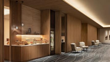 A modern hotel lobby with a reception desk, seating area, and a patterned carpet.