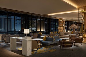 A modern lounge area with sofas, tables, and a large window offering a city view. - Courtyard by Marriott Nagoya (Nagoya)