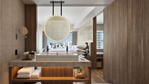 A modern bathroom with a large sink, wooden vanity, and a view of the city.