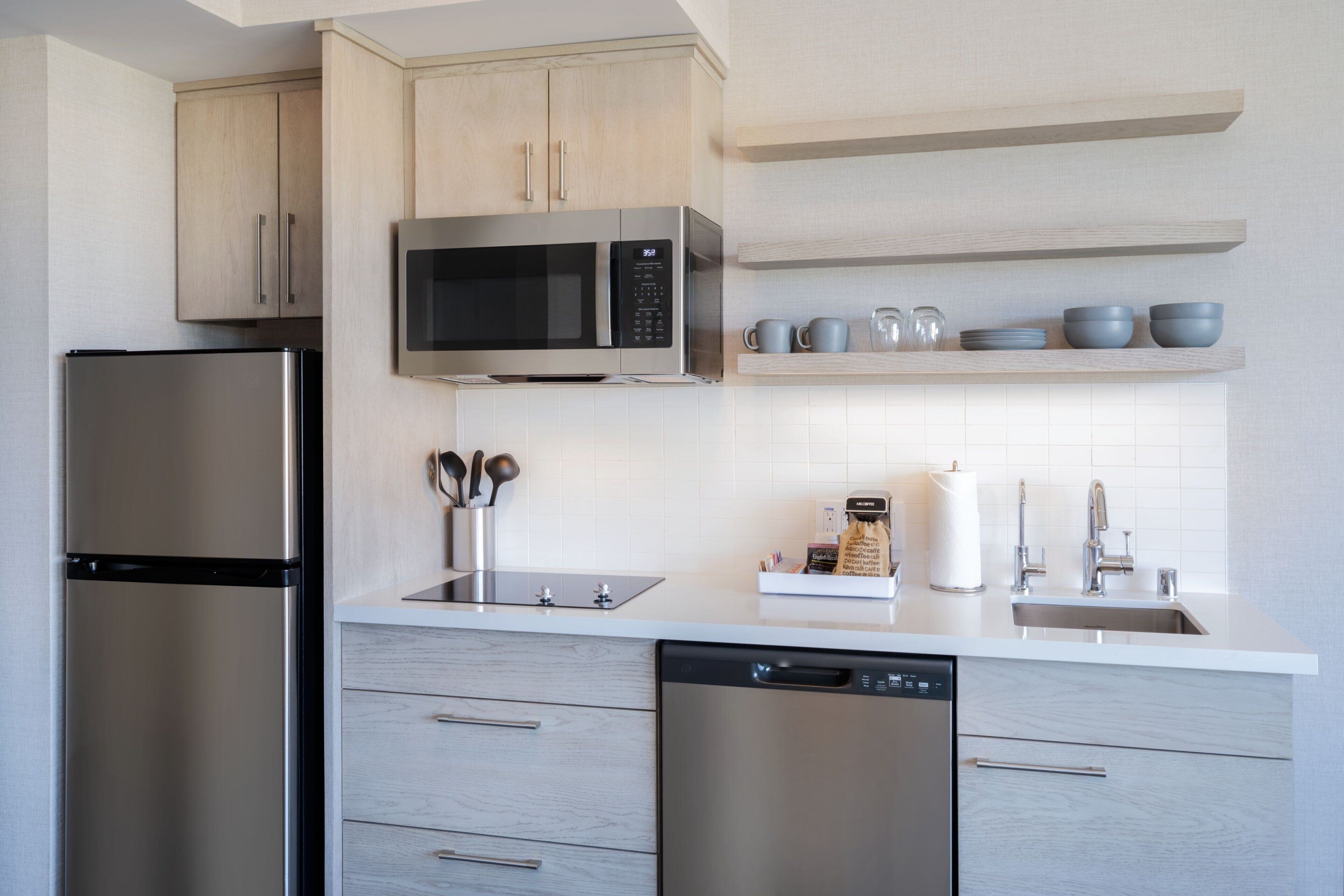 A modern kitchen with stainless steel appliances, wooden cabinets, and a white countertop.