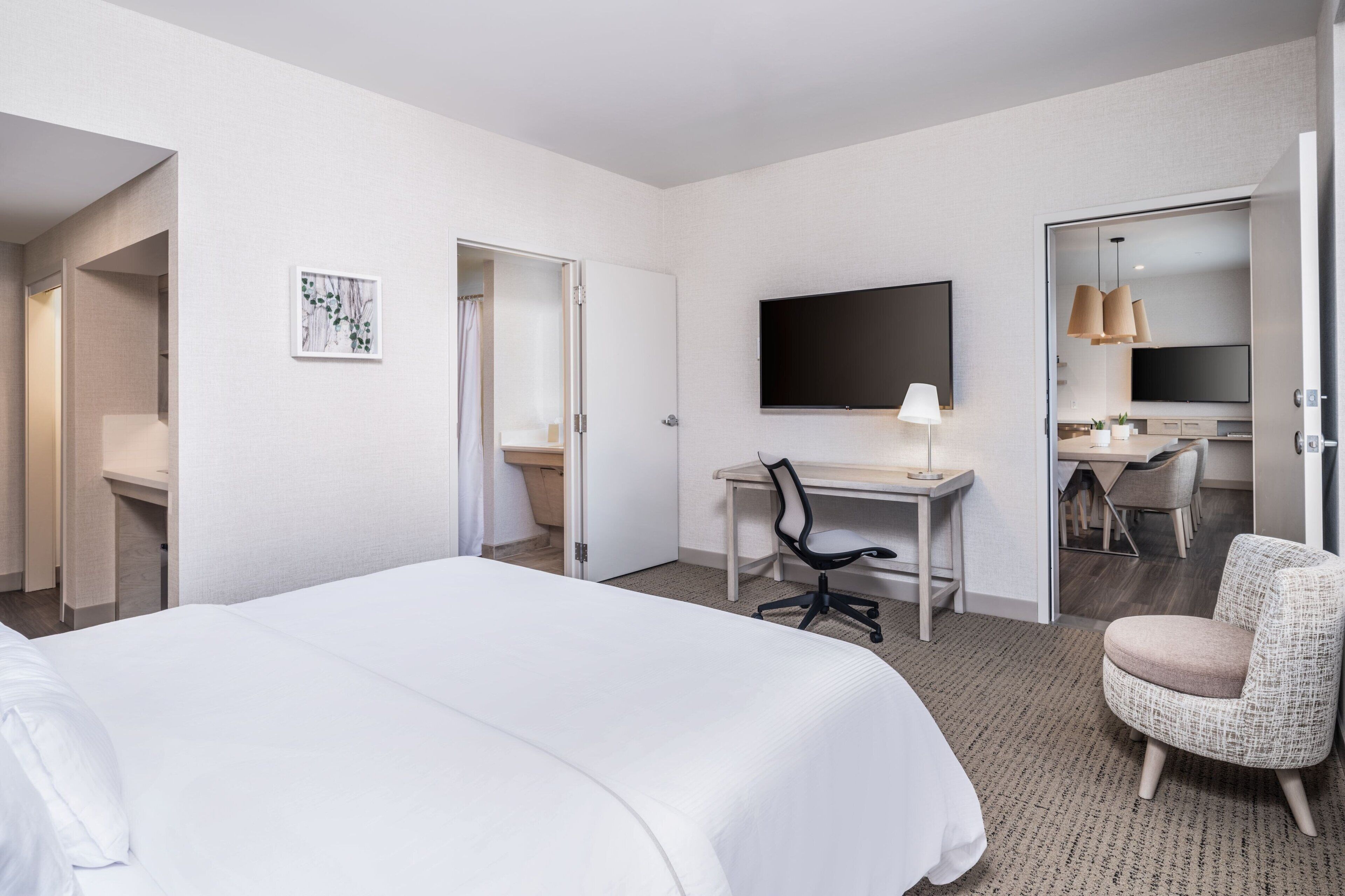 Une chambre d’hôtel avec un grand lit, un bureau, une chaise, une télévision et une salle de bain.