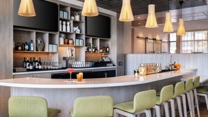 Eine moderne Bar mit einer langen Theke, mehreren hängenden Pendelleuchten und Barhocker.