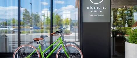 A green bicycle parked in front of a building with a sign reading "element by Westin San Jose Airport".
