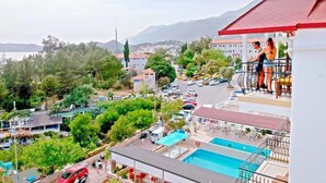 A hotel with a pool, a view of the city, and a mountain in the background. - Ferah Hotel (Kaş)