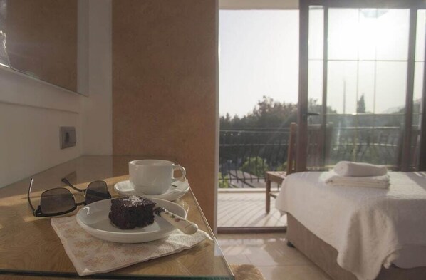 A hotel room with a balcony, a bed with a white blanket, a table with a plate of food and a cup, and a pair of sunglasses on the table. - Ferah Hotel (Kaş)