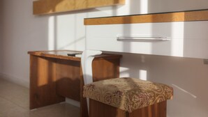 A small, modern room with a wooden desk and a chair, a white wall with a wooden panel, and a mirror above the desk. - Ferah Hotel (Kaş)