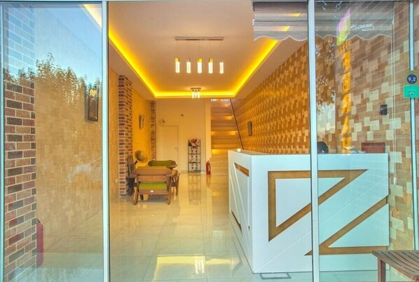 A reception area with a modern design, featuring a reception desk, seating area, and a staircase leading to an upper level. - Ferah Hotel (Kaş)