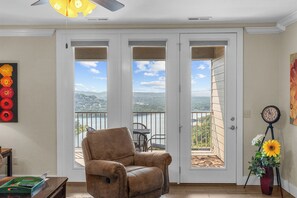 A room with a brown leather chair, a table with a book, and a painting of flowers on the wall. - Lake View Condo, Newly Renovated with Community Pool & Free Tickets, Near Silver Dollar City (Branson)