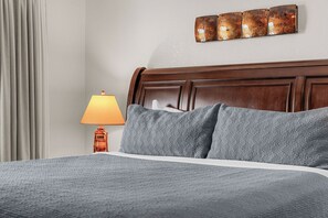 A hotel room with a bed, a nightstand with a lamp, and a wall-mounted artwork.