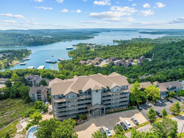 A multi-story hotel with a central courtyard, surrounded by lush greenery and a body of water.