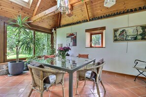 Un coin repas avec une table en verre, des chaises en osier et une plante en pot.
