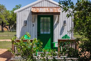 Un petit bâtiment rustique avec une porte verte et le chiffre « 3 » peint sur le mur.