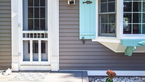 A house with a front door, a window with a fish-shaped decoration, and a porch with a doormat. - Peace and Quiet & Spacious Back Deck (Wellfleet)