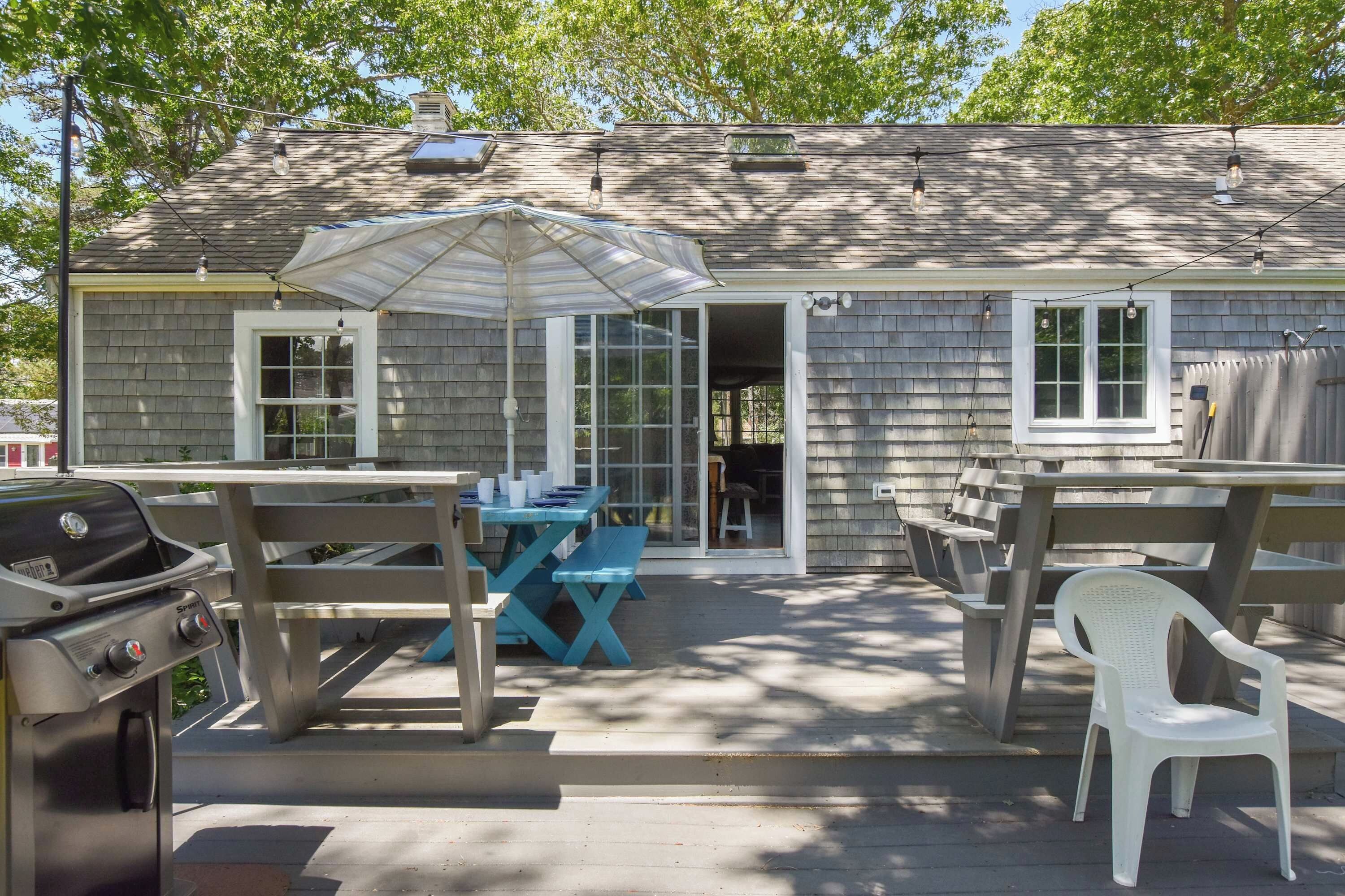 A house with a patio area featuring a grill, a table with chairs, and an umbrella.