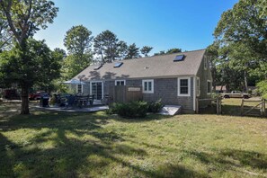 A single-story house with a covered patio, a fenced yard, and a vehicle parked outside. - Peace and Quiet & Spacious Back Deck (Wellfleet)