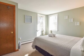 Une chambre à coucher avec un lit, une porte et des fenêtres.