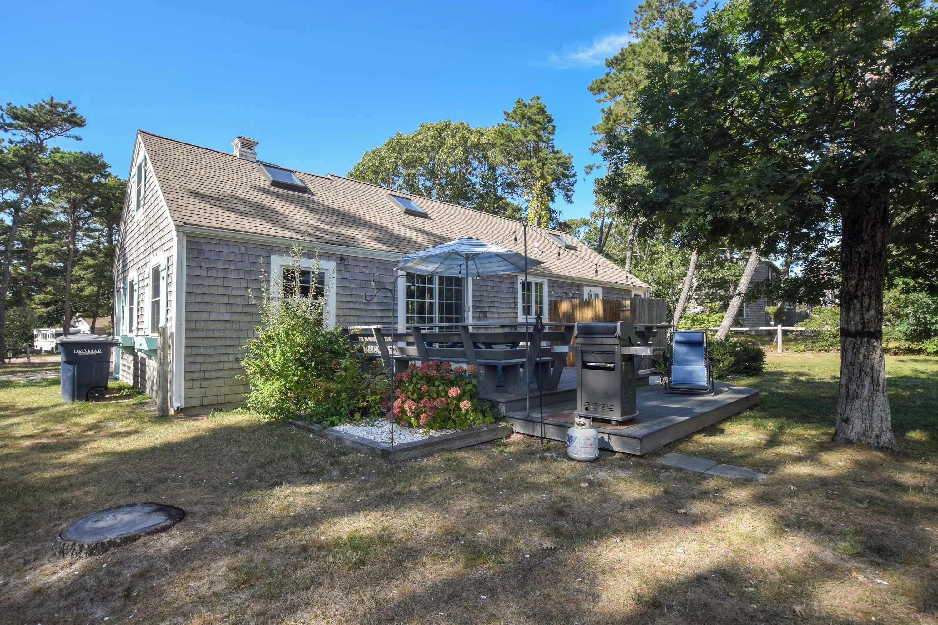 A single-story house with a covered patio area, a chimney, and a small garden with flowers.