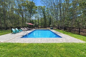 A rectangular swimming pool with a paved deck, surrounded by a black metal fence, and green lawn chairs. - Heated In-Ground Pool and New Central AC! (Brewster)