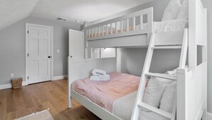 A bedroom with a bunk bed, a door, a white wall, and a wooden floor. - Heated In-Ground Pool and New Central AC! (Brewster)
