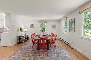 A dining area with a round table, red chairs, a rug, and artwork on the walls.