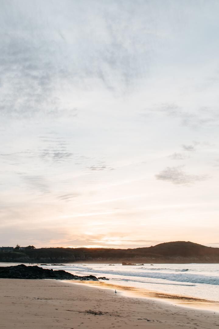 Una playa con cielo despejado y una colina distante.
