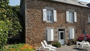A stone building with a gravel driveway, white shutters, and outdoor seating. - Le Clos Neuf - SAINT-GUINOUX (SAINT-GUINOUX)