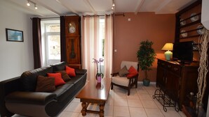 A living room with a sofa, armchairs, a coffee table, a clock, a television, and a potted plant. - Le Clos Neuf - SAINT-GUINOUX (SAINT-GUINOUX)