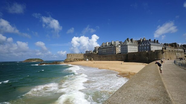 A coastal cityscape with a prominent historic building, a sandy beach, and a rocky outcrop in the distance. - Le Clos Neuf - SAINT-GUINOUX (SAINT-GUINOUX)