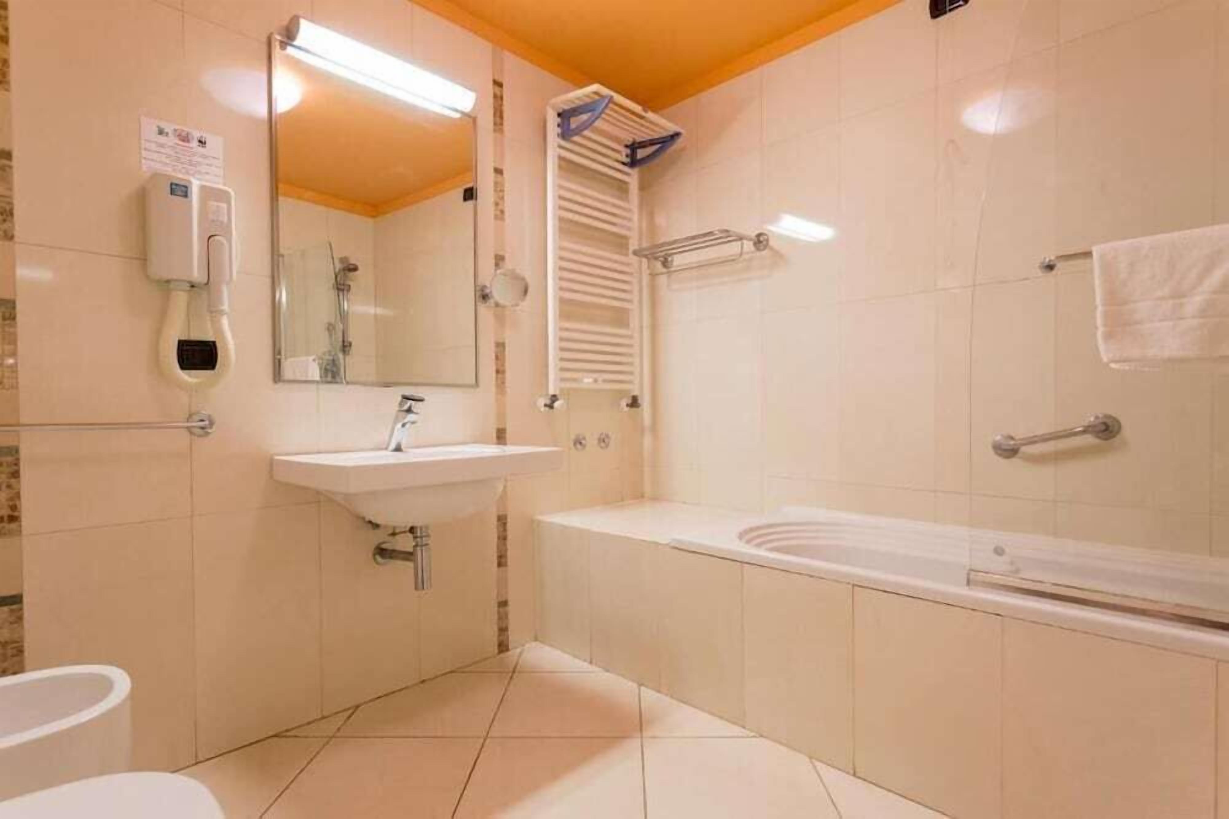 A bathroom with a sink, mirror, towel rack, and a bathtub.