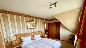A hotel room with two beds, a desk, a chair, a wardrobe, and a mirror. - Moby Dick Wustrow (Ostseebad Wustrow)