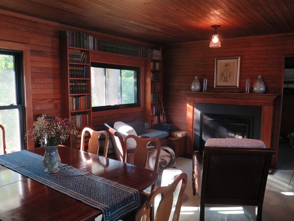 Un intérieur chaleureux en bois, avec une cheminée, des étagères à livres et un coin repas.