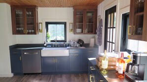 Une cuisine moderne avec des meubles de couleur sombre, un grand îlot central et une machine à café.