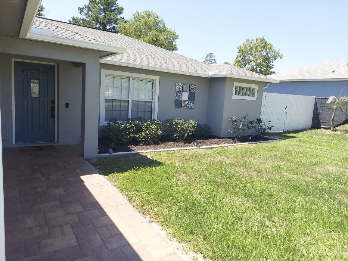 A residential house with a front yard, a brick pathway, and a garage.