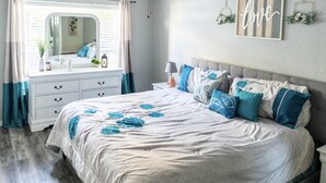 Une chambre à coucher avec un grand lit, une commode, une table de chevet et un miroir.