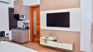 Ein modernes Hotelzimmer mit Küchenzeile, einem flachbildfernseher an der Wand und einer Wandverkleidung aus Holz.