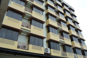 A multi-story building with a modern architectural design, featuring a series of balconies and air conditioning units on the exterior. - Rumah Highlands Hotel (Cebu)