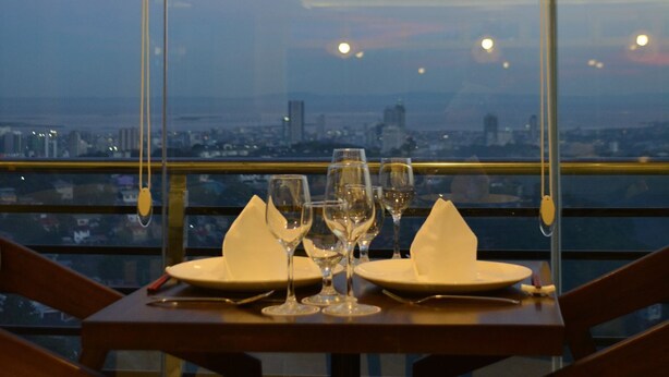 A table set for two with a city view through large windows. - Rumah Highlands Hotel (Cebu)