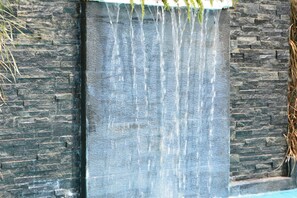 A waterfall feature with a stone wall backdrop. - Rumah Highlands Hotel (Cebu)