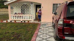 Een woning met een bestrate oprit, een garage en een geparkeerde auto.