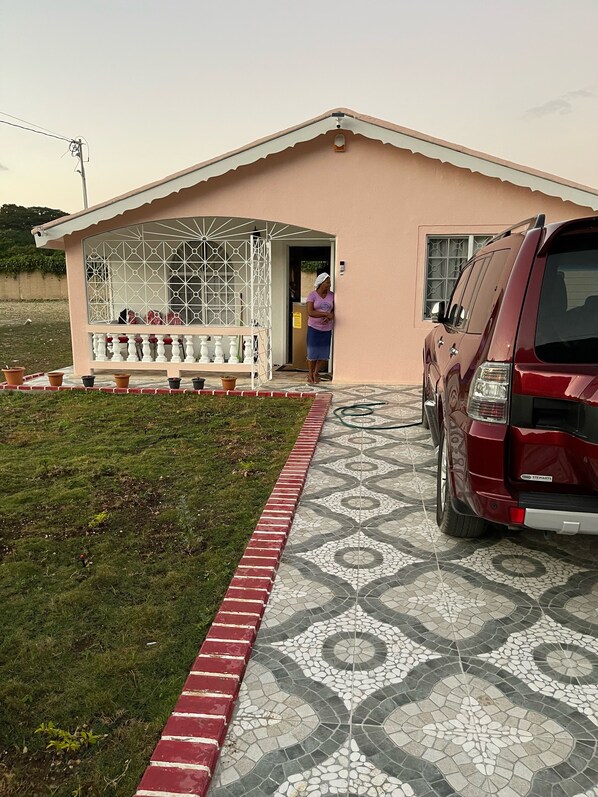 Une maison avec une allée carrossable dallée, un garage et un véhicule garé à l’extérieur.