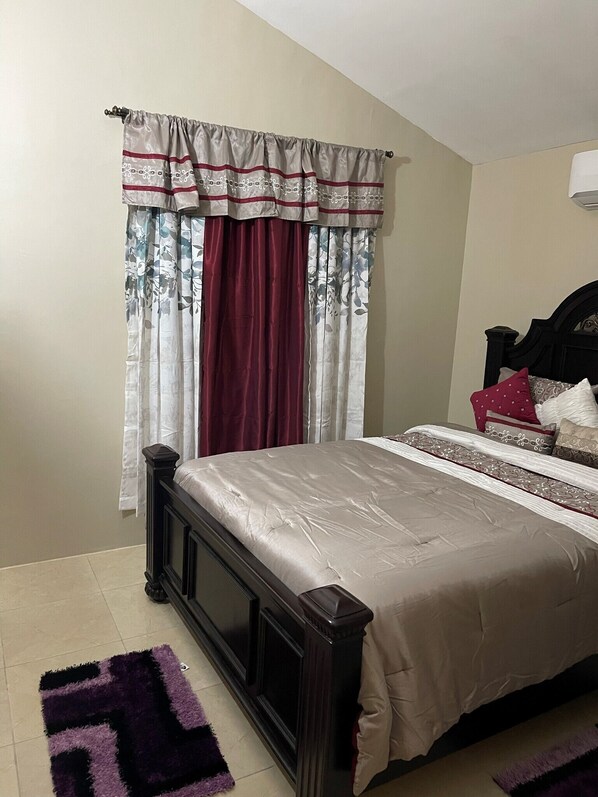 Une chambre à coucher avec un lit, des rideaux, une tête de lit et un tapis.