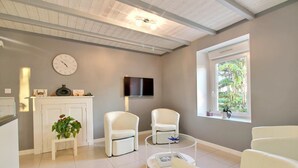Uma sala de estar moderna com lareira, móveis brancos, um relógio e uma televisão.