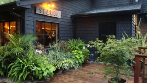 A building with a sign reading "SILVIA" and a wooden deck with various potted plants.