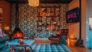 A cozy living room with a fireplace, a bookshelf, a couch, and a Netflix sign.