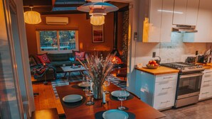 A modern kitchen with white cabinets, a built-in oven, and a dining area with a wooden table and chairs.